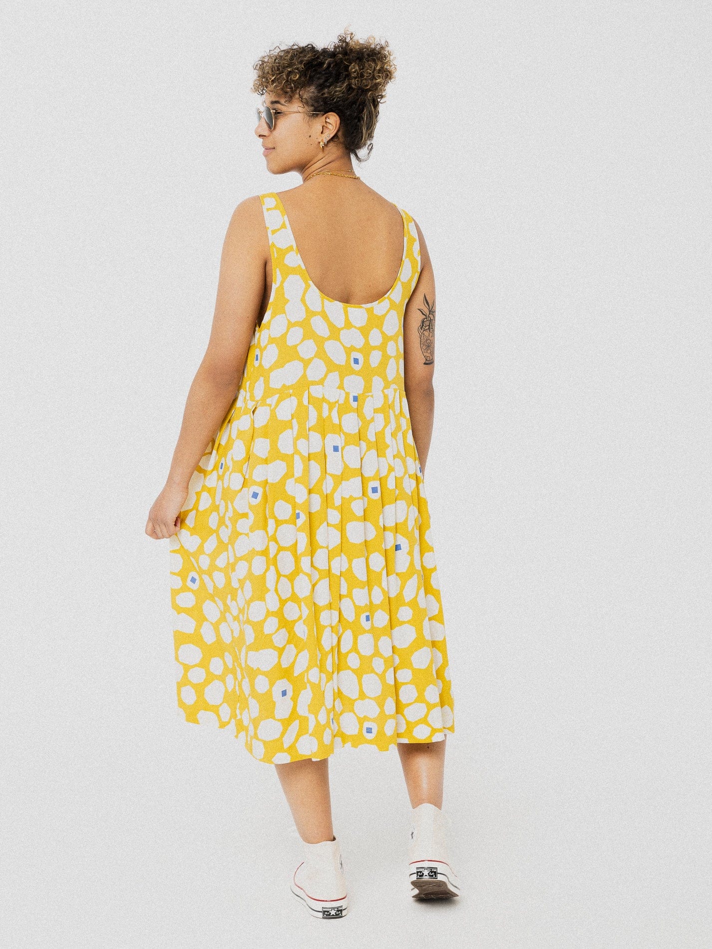 Robe d'été longue ample et confortable jaune avec des ronds asymétriques blancs, et avec des bretelles ajustables.